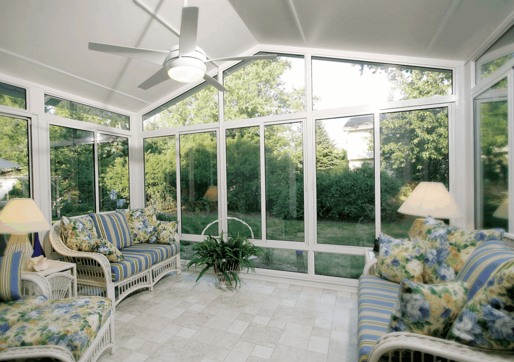 Sunroom featuring wicker furniture with floral cushions, large windows providing natural light, and a ceiling fan, emphasizing outdoor living and relaxation.